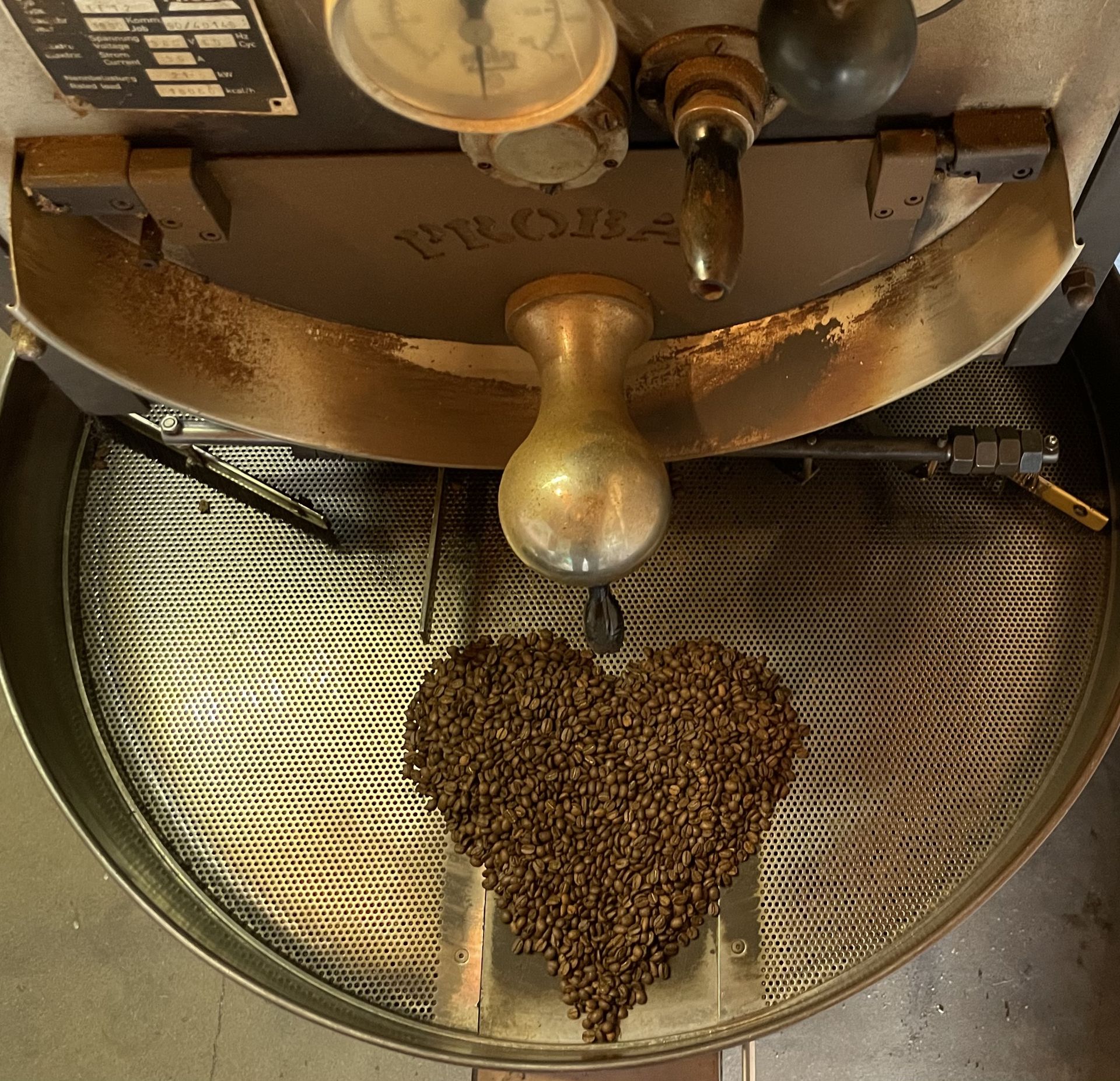 Kühlsieb der Röstmaschine aus Vogelperspektive mit einem Herz aus gerösteten Kaffeebohnen Feinkost Kaisen - Kühlsieb der Röstmaschine aus Vogelperspektive mit einem Herz aus gerösteten Kaffeebohnen