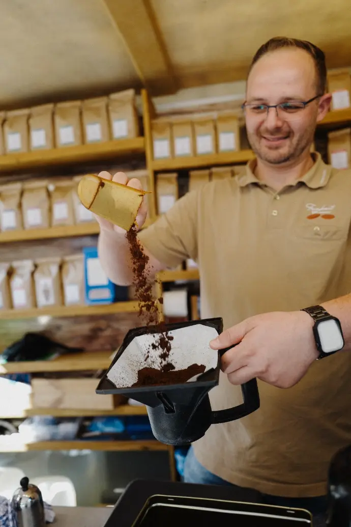 Feinkost Kaisen - Das Einfüllen von gemahlenem Kaffee in einen Kaffeefilter für eine Kaffeemaschine